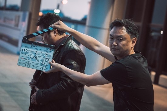 촬영 현장에서 슬라이드를 들고 있는 강윤성 감독 모습